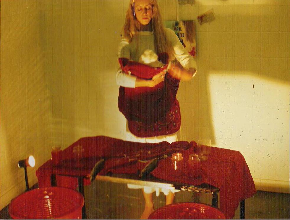 photo of performance with artist holding a lard baby next to table with a red table cloth and mackerel