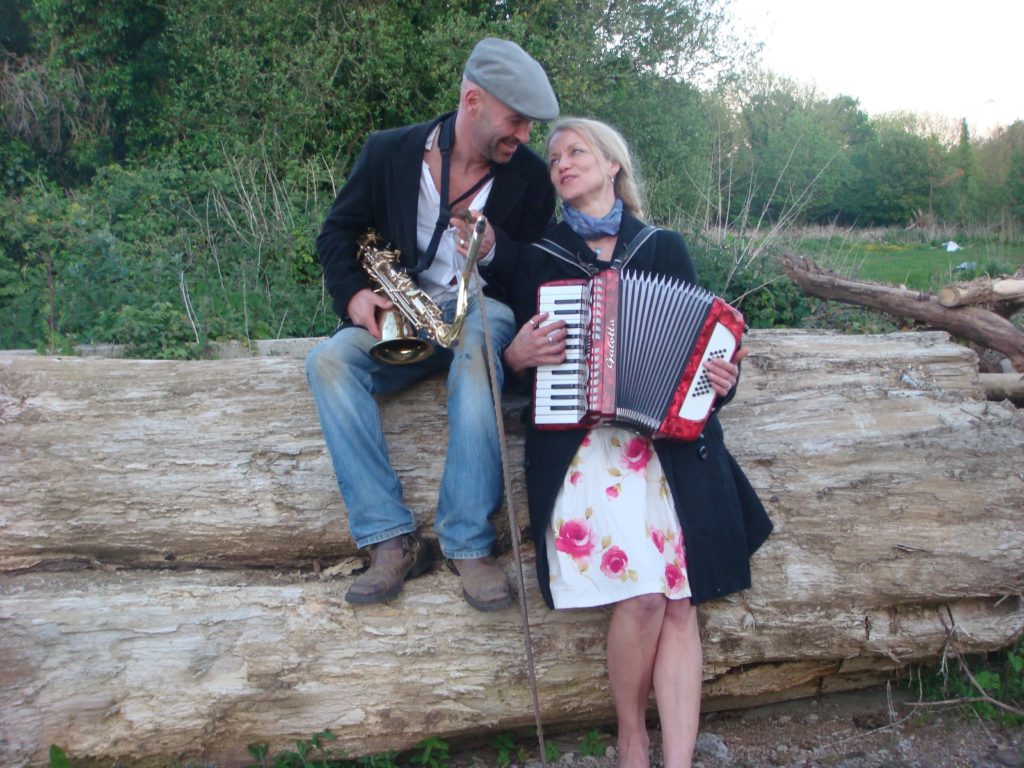 photo of nigel )sax) and delph (acorrdion on a log outside